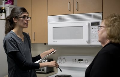 Student helping a senior in the kitchen