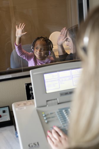 child raising her hand during hearing test