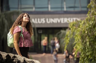 Student standing outside the main entrance of Salus