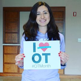 student holding OT month sign