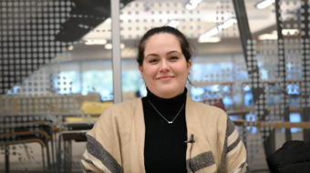 Student Angela Rios show in black turtle neck and cream sweater in front of window.