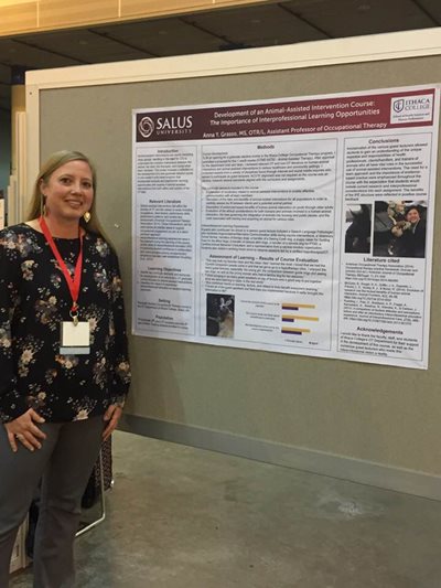 Anna Grasso standing in front of a poster presentation of her research on the development of animal-assisted intervention course: the important of interprofessional learning opportunities