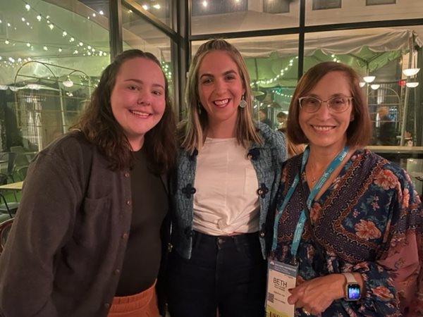 Three salus faculty and alumni standing at the happy hour smiling at the camera