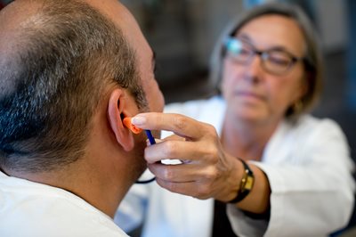 audiologist putting ear plugs in patient's ear