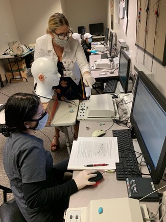 Audiology professor instructing student in lab.