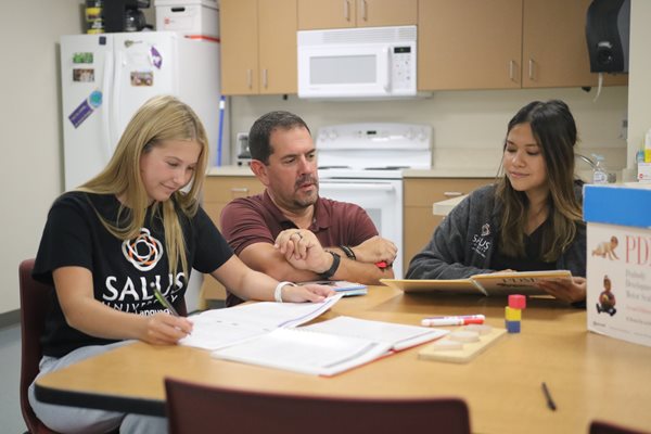 Bob Serianni talking with students sitting at a table