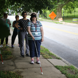 BLVS student using a white cane on the sidewalk