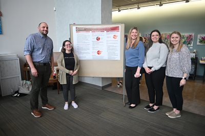 SLP students smiling in front of their capstone poster