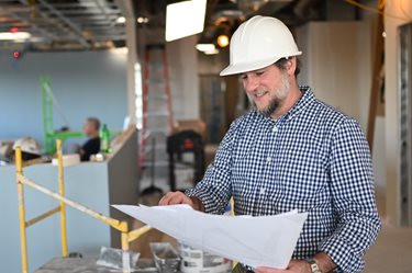 Dr. Duncan wearing hard hat examining floor plans