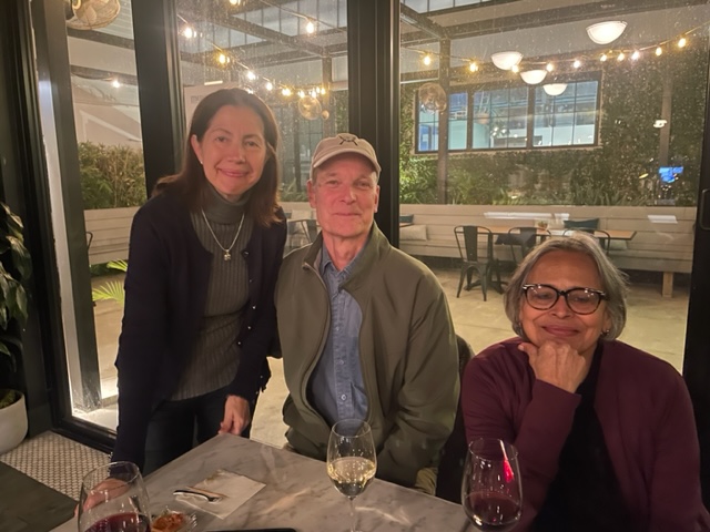 Three people sitting at a restaurant smiling for a group photo