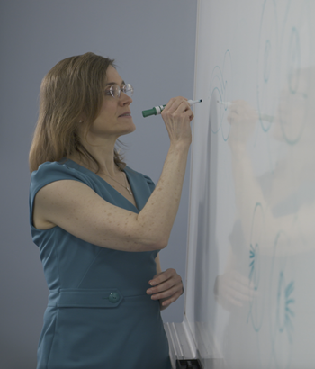 Dr. ​Kelly Malloy writing on a white board