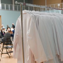 Long white coats hanging on a clothing rack