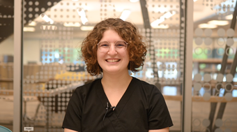 Student Madison Matello shown in black scrubs in front of window.