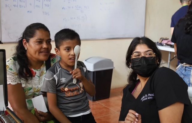 PCO student working giving an eye exam to a young boy