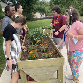 TVI students tactually exploring basil and rosemary in the sensory garden.