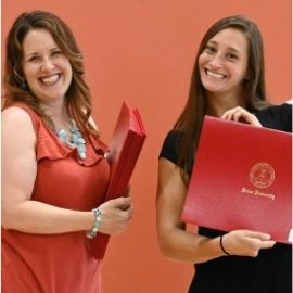 OT student holding her diploma next to a faculty member