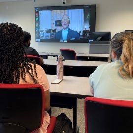 Two students watching Dr. Donald Smith on Zoom