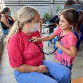 Young girl using a stethoscope on a faculty member