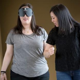 Student guiding a person with an eye covering