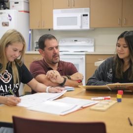 SLP faculty member helping two students study