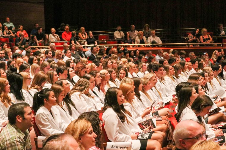 Students sitting at the ceremony in their white coats