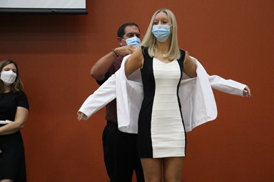 Student receives white coat from Bob Serianni