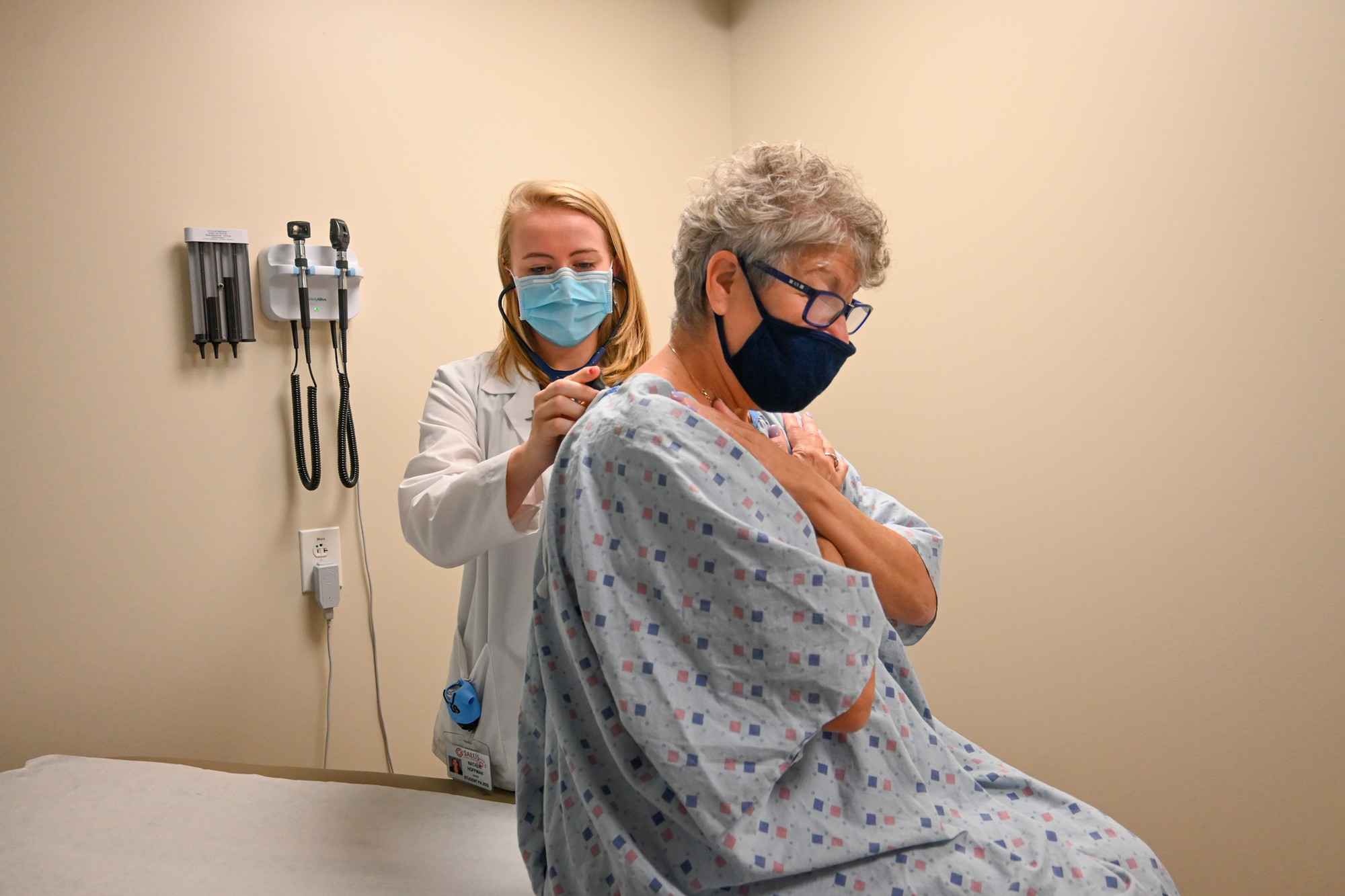 student performing wellness exam on older woman