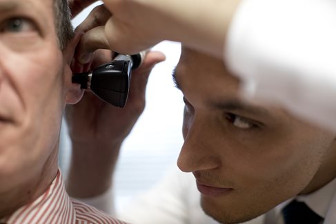 Audiologist providing an ear exam to a male patient