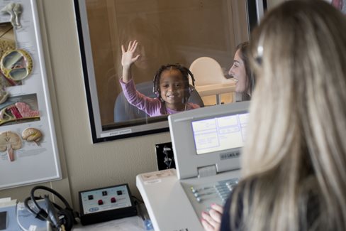 girl raising her hand during hearing exam