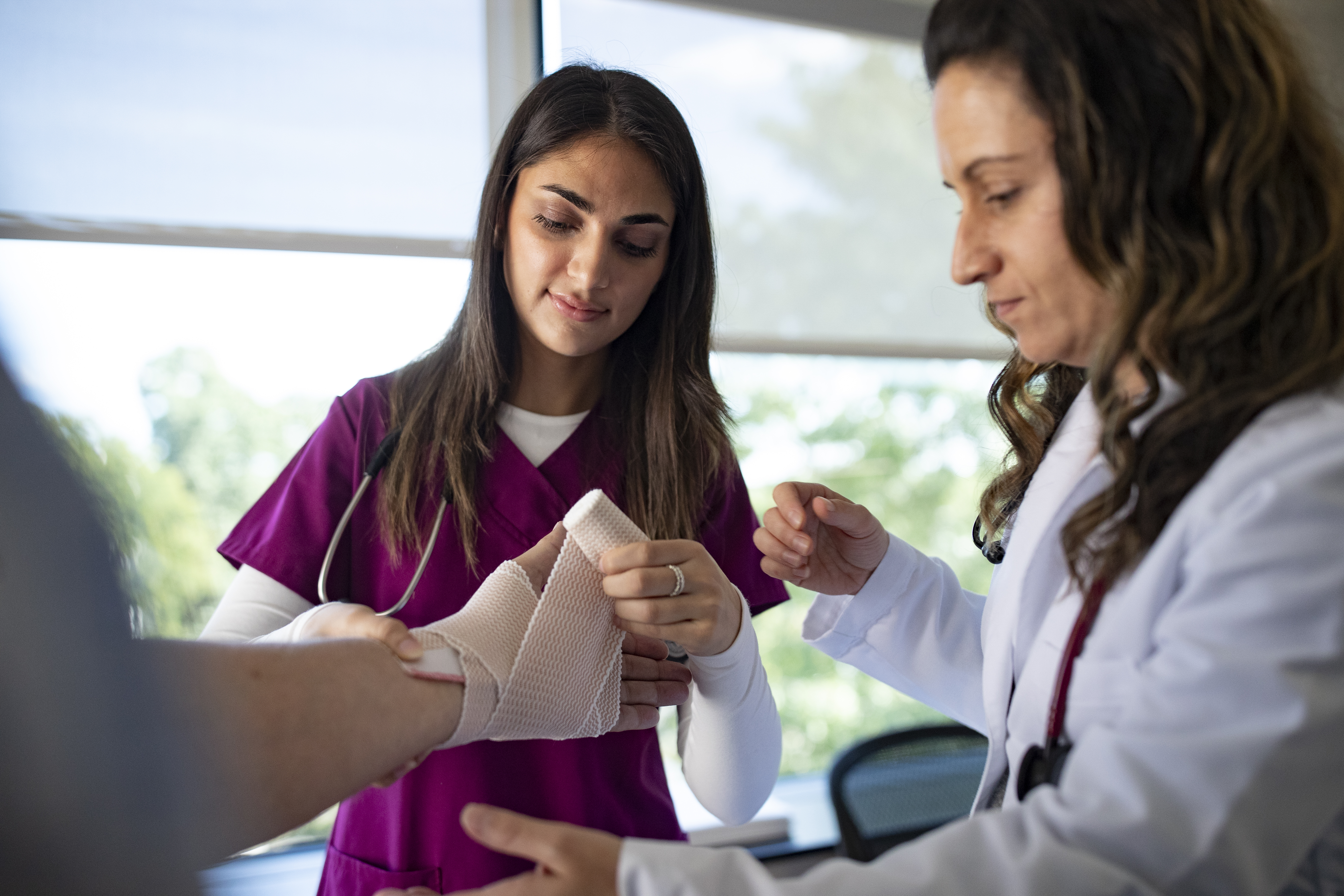 Student and faculty wrapping a patients hand