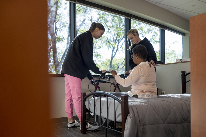 OT student helping a patient into bed