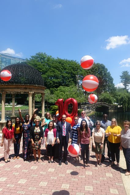 Salus faculty, staff and students throwing beach balls and holding "10" balloons