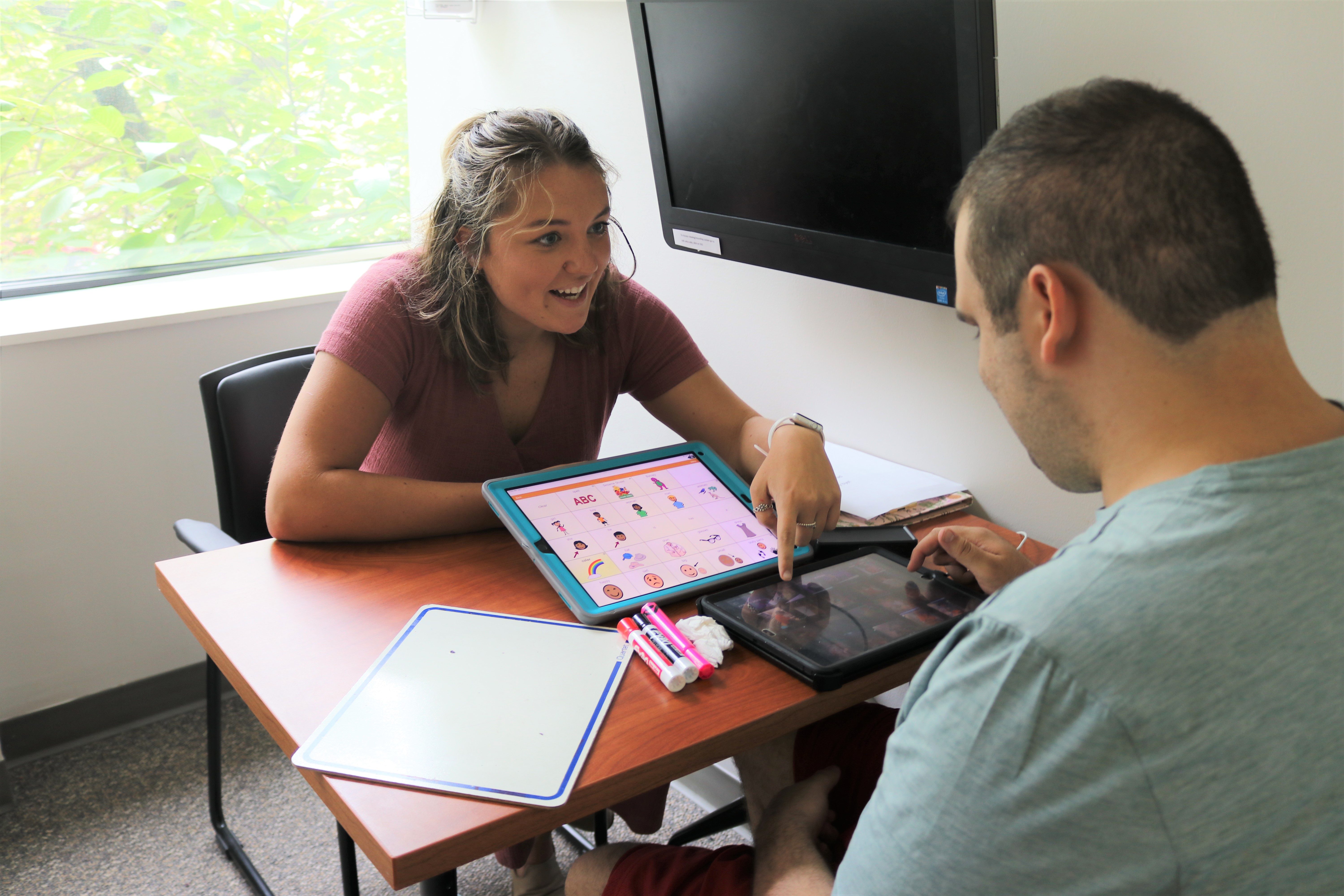 Student helping client with AAC device