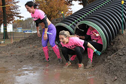 students going down slide into mud