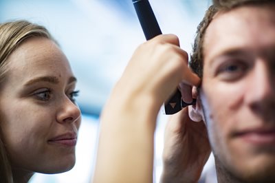 Student giving a patient an ear exam with an otoscope