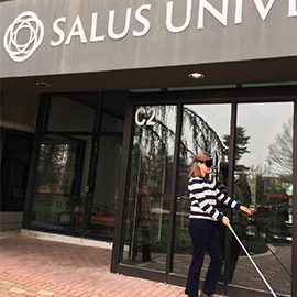 Woman walking around Salus with a white cane