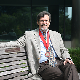 Dr. Victor Hugo Bray sitting on a bench wearing his presidential medal