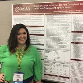 Caitlin in front of her poster at ASHA