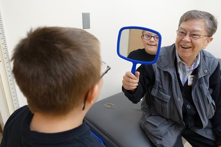 Cathie showing a student their glasses in a mirror