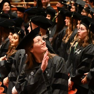 Graduate waving to family thumb