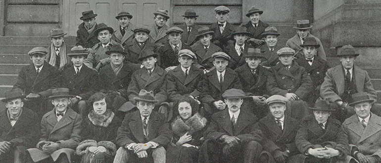 Black and white group photo of PCO graduates sitting on steps