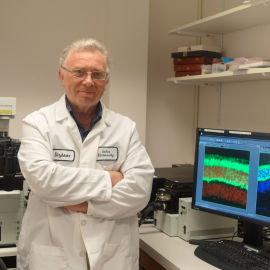 Dr. Dizhoor standing in front of a computer with his arms crossed