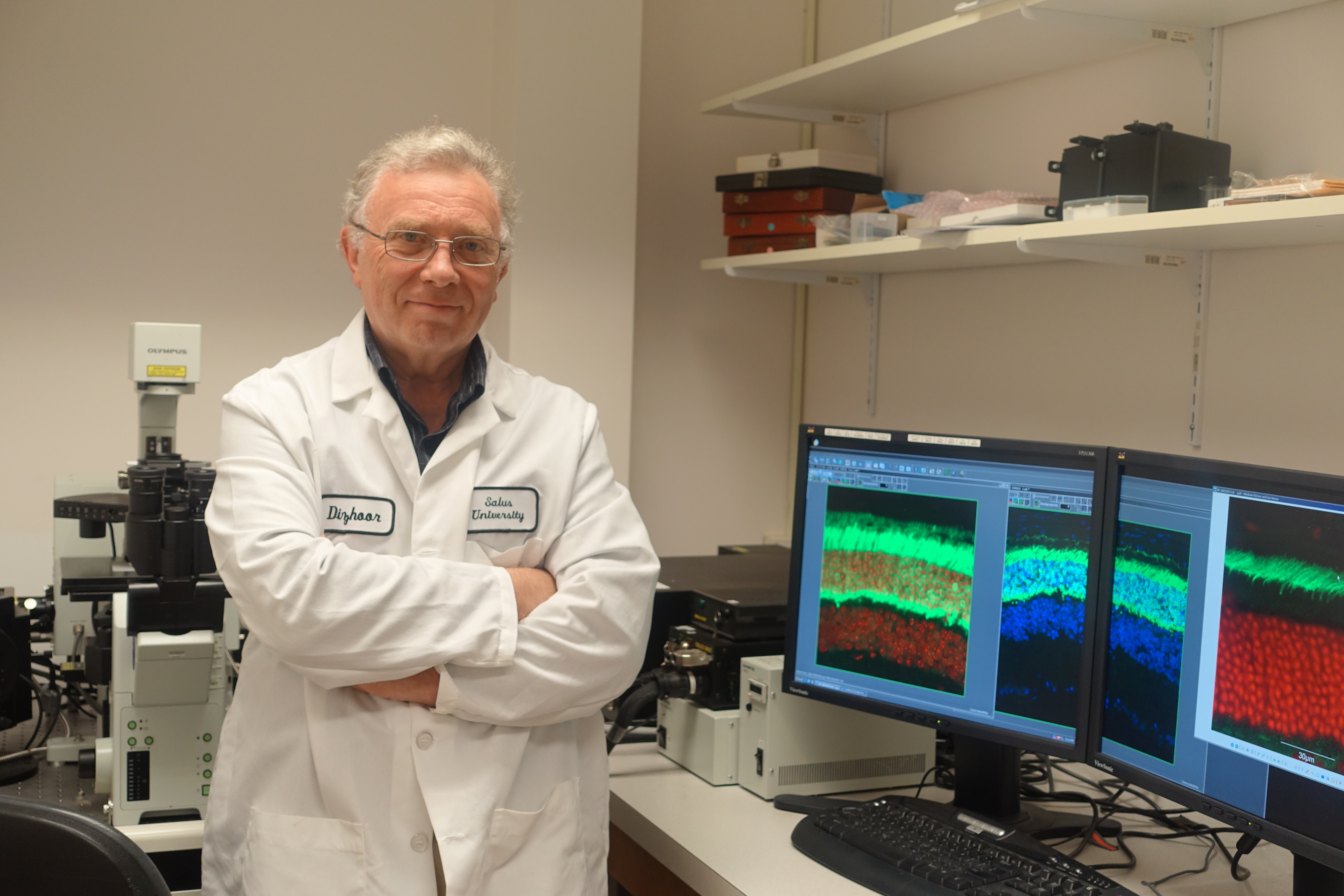 Dr. Dizhoor standing with his arms crossed in front of a computer