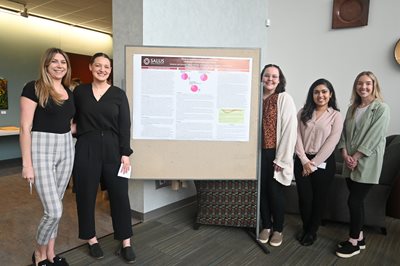 SLP students posing and smiling with their capstone poster