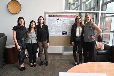 SLP students smiling in front of their capstone poster