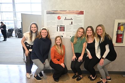 6 SLP students with their advisor standing in front of their capstone poster