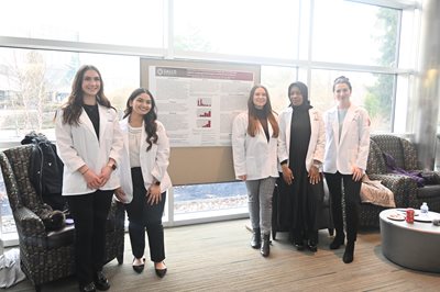 5 SLP students standing in front of their capstone poster