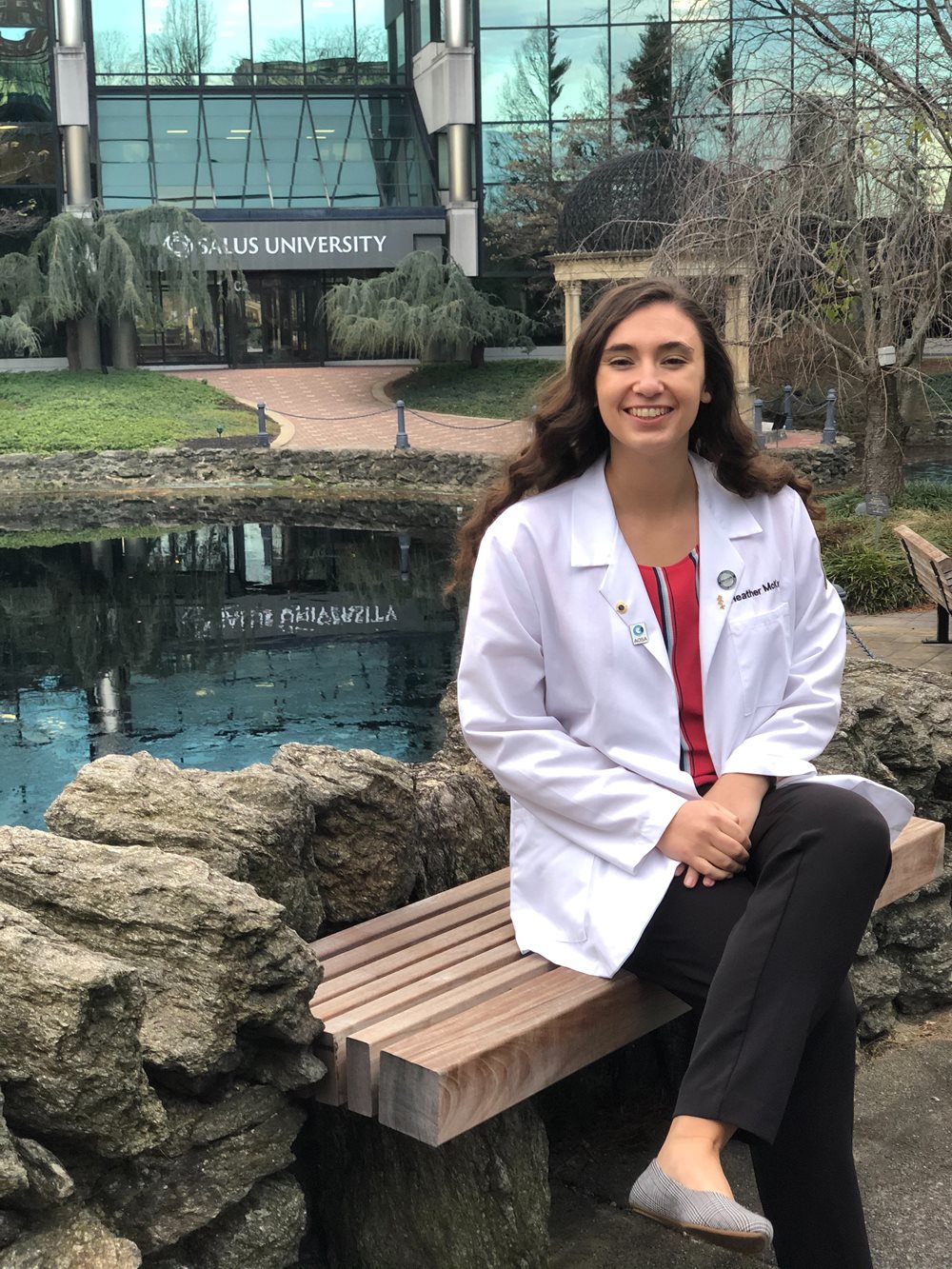 Heather McKay wearing her white coat outside of the Salus University main entrance