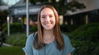 Student Kierra Wells shown in blue shirt with a Salus building and greenery blurred in background