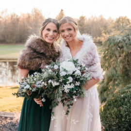 Megan Schafer holding a bouquet of flowers on her wedding smiling with a bridesmaid